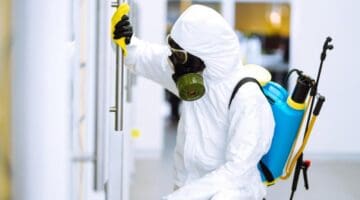 person-wearing-hazmat-suit-disinfecting-a-door